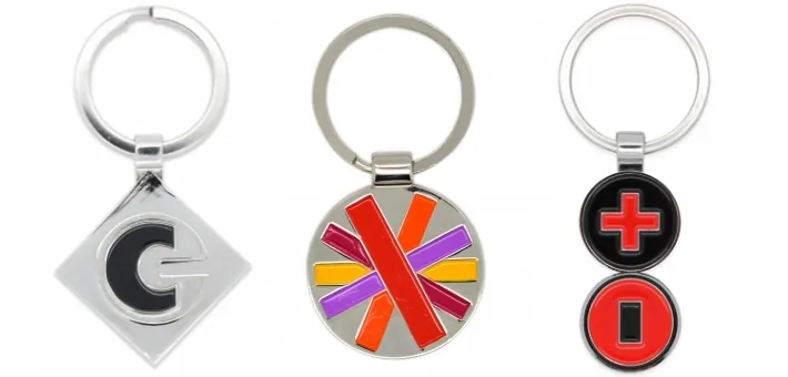 Tres llaveros de metal esmaltados con logos de empresa
